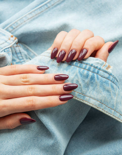 istock Elegant hands with polished burgundy nails resting on a denim jacket sleeve showcasing a stylish look in natural light 2175806099