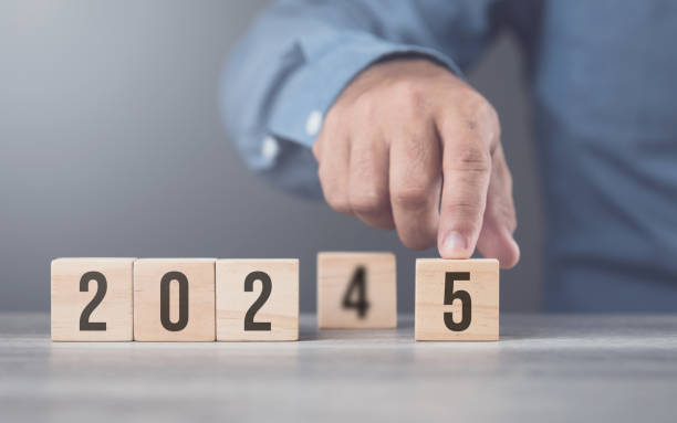 istock Hand replaces 2024 with 2025 using number blocks, symbolizing the transition into the new year, representing change, progress, and the ongoing passage of time 2175808173