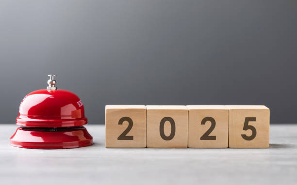 Red service bell and a wooden block displaying 2025 are placed side by side, symbolizing a call to action for the new year. The scene highlights themes of preparation, planning, and fresh beginnings