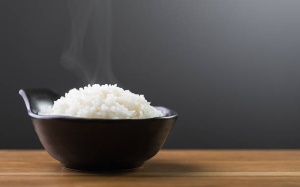 istock Cooked Thai jasmine rice served in a black bowl sits on a brown table against a dark grey backdrop. The studio shot highlights the fluffy texture and aromatic quality of the rice 2175809161