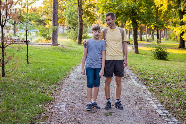 Connecting with nature. Father and son exploring forest in autumn and learning about plants.