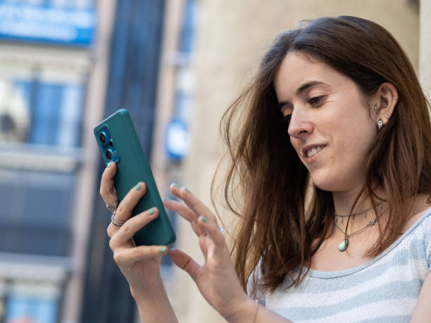 istock Young woman using her smartphone in an urban setting on a sunny day 2175817540