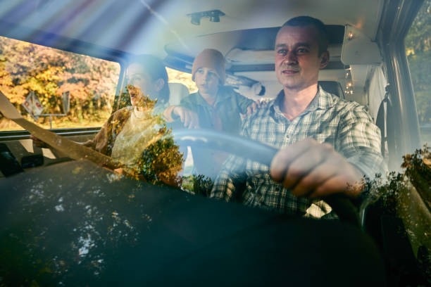 Carefree family going on a trip in a van. Carefree father and his family going on a road trip in camper trailer. The view is through glass. family-van-driving stock pictures, royalty-free photos & images