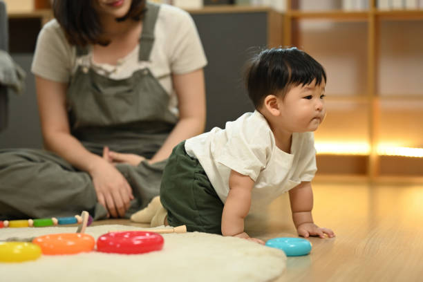 istock Little baby boy learning to crawl with supportive mother closely watching from behind. Childhood and development concept 2175822916