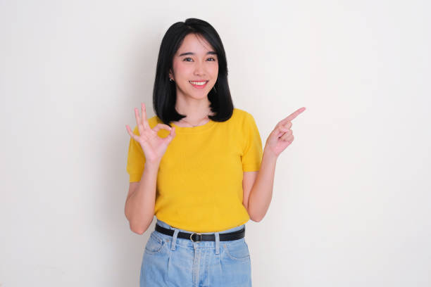 istock A woman smiling give OK hand sign while pointing beside her 2175830920