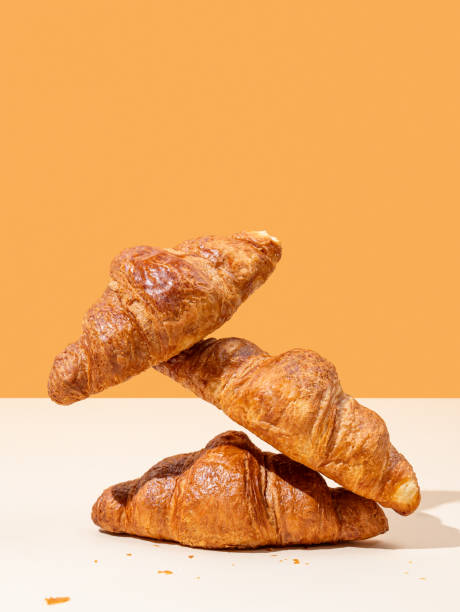 istock Stack of fresh croissants on yellow and orange background. Creative trendy layout and concept of healthy food or french breakfast 2175831894