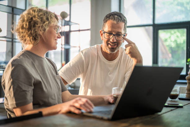 istock Mature Couple Enjoys Coffee While Browsing Laptop in Sunny Dining Room 2175835594