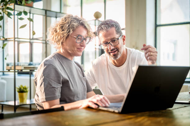 Mature Couple with Coffee Using Laptop in Bright Dining Area