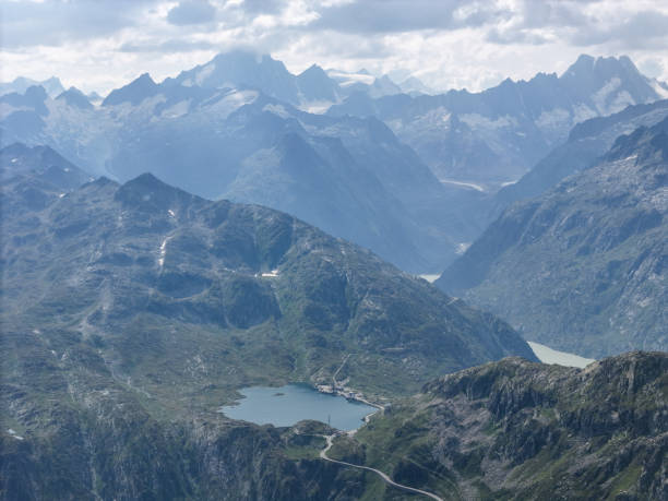 A breathtaking aerial view of towering mountains and serene alpine lakes, showcasing the grandeur of the landscape under a misty sky.