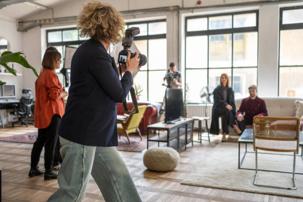 A photographer captures the essence of diverse models in a bright studio setting, as they engage with the camera in stylish outfits, with a dynamic teamwork vibe evident in the background.