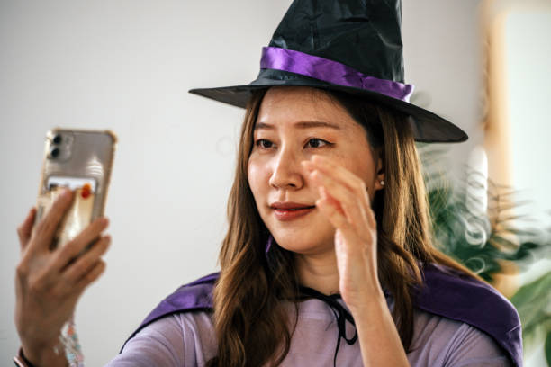 Smiling young woman taking selfie in halloween decorated room