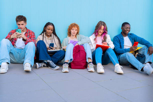 istock A group of diverse young people sitting outdoors using smartphones and notebooks 2175844559