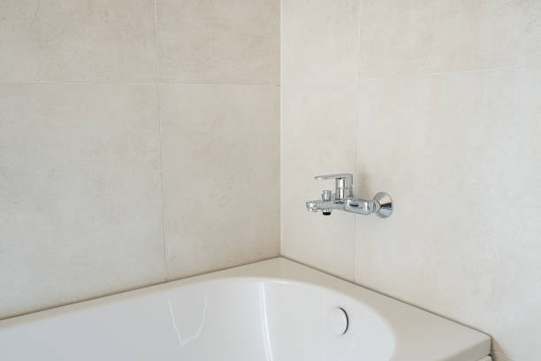 Bathtub and faucet in modern unfinished bathroom, selective focus