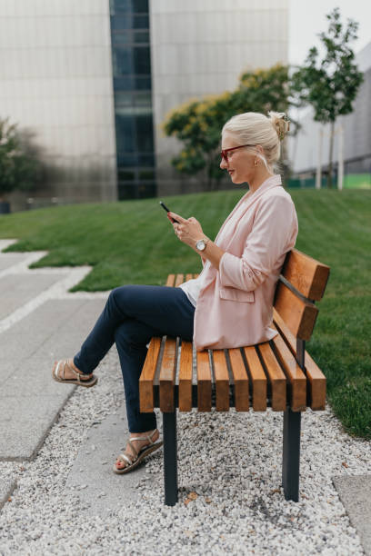 istock Woman happily engaged with phone on park bench. 2175849305