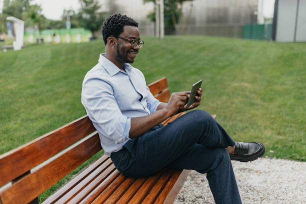istock Casual man enjoying tablet on park bench, relaxed scene 2175850103