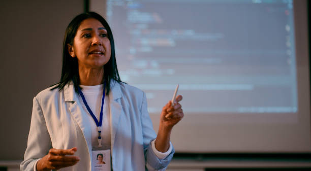 Confident Female Lecturer Conducting a Coding Lecture in Low Light Classroom Setting stock photo