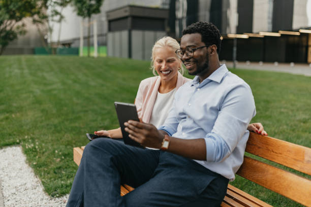 istock Smiling duo engaged with a tablet on a bench outdoor 2175850628