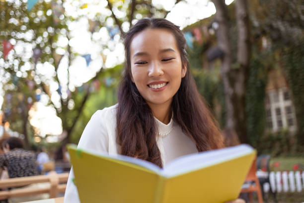 istock Beautiful Asian Woman Reading a Book While Relaxing in the Cafe 2175851204