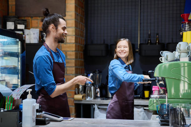 istock Two cafe workers working together behind counter, at coffee shop 2175854558