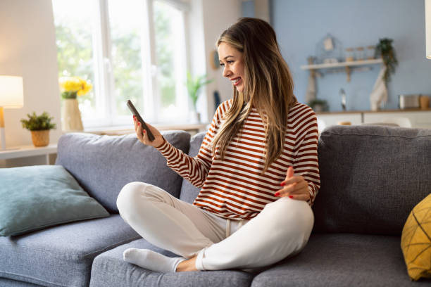 istock Young Caucasian woman using mobile phone for online purchases, while sitting on the sofa 2175856661