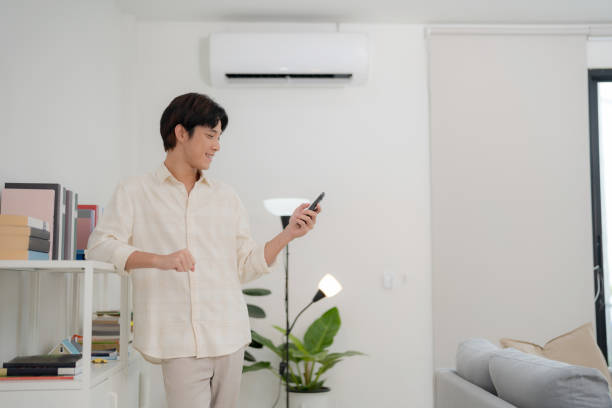istock Young man using smart thermostat app in modern living room 2175859660