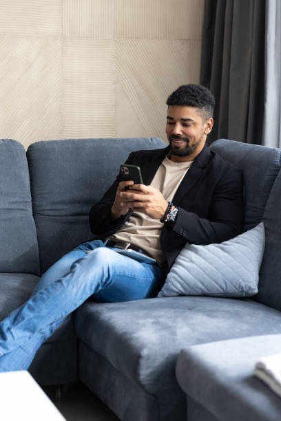 istock Handsome black man joyfully using his mobile phone while smiling and texting to his friends 2175866516