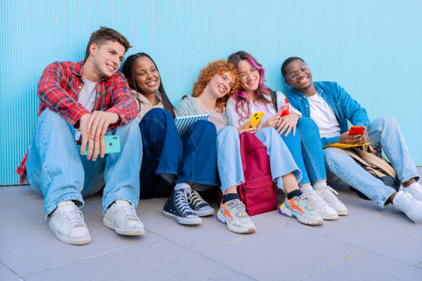 istock Diverse young people sitting outdoors using smartphones looking at camera 2175866517