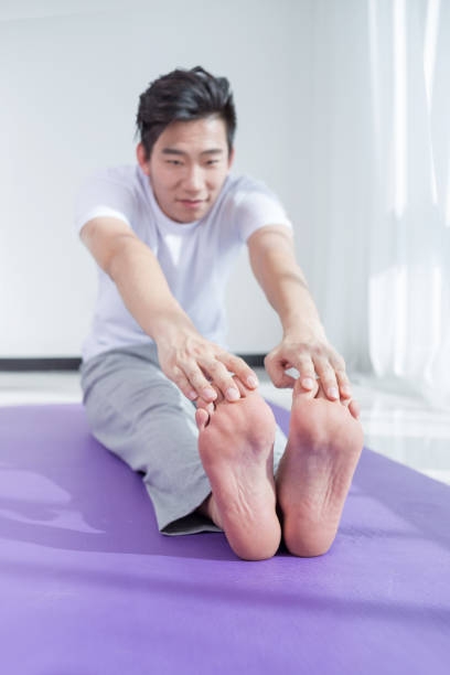 Rear view of a healthy mid adult man stretching his hands while standing outside on a summer day