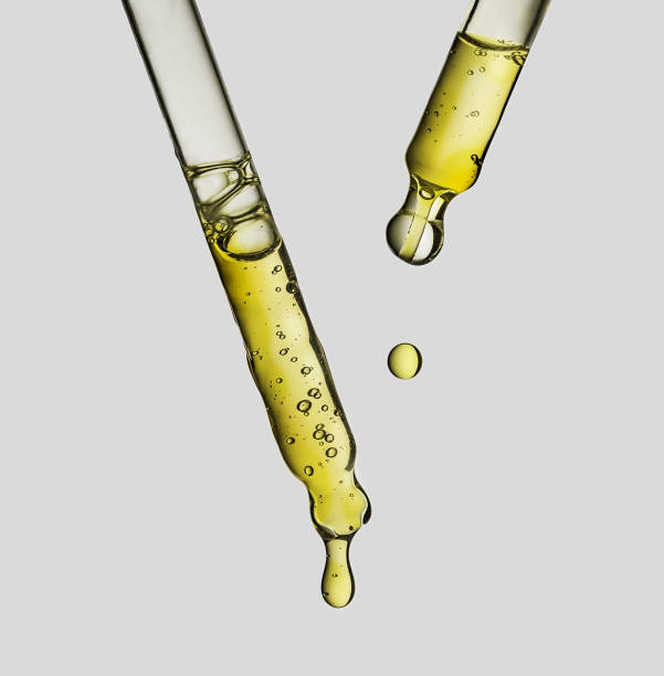 Dropper pipette with yellow serum with texture drops on white background