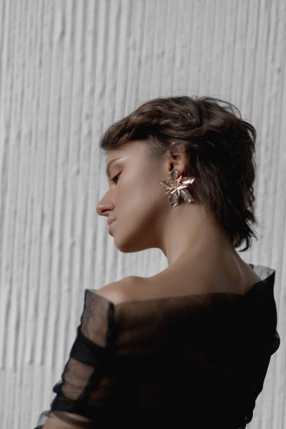istock Young woman showcases her modern hairstyle and statement earrings while posing elegantly 2175876551