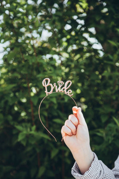 Hair hoop with the inscription Bride in female hand, bride to be party concept. Hair hoop with the inscription Bride in female hand, bride to be party concept. Female headband for wedding, hairpins for hair. Bride accessories, hair holder. The inscription bride on the headband. hoops wedding stock pictures, royalty-free photos & images