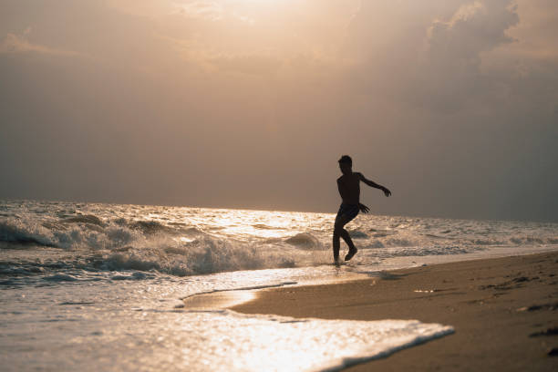 Happy boy playing with waves at the beach