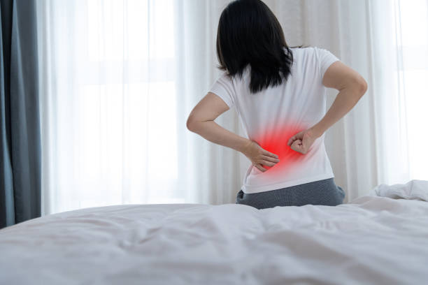 istock Women with lower back pain sitting by the bed 2175889890