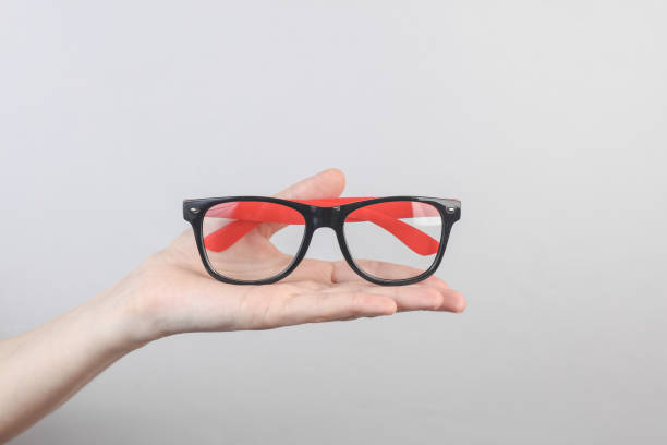 Hand holding eyeglasses on gray background