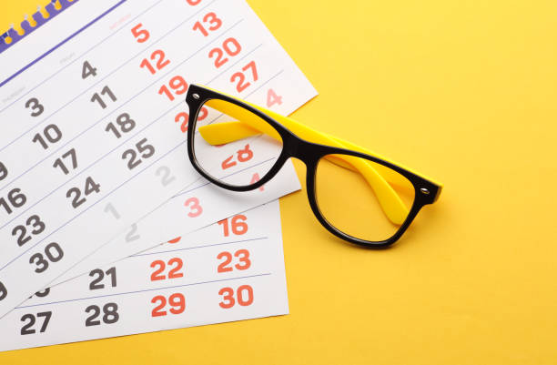 istock Eyelasses and calendar sheets on a yellow background 2175896167