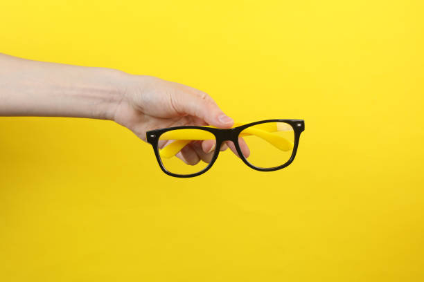 istock Hand holding eyeglasses on yellow background 2175896253