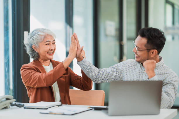 istock Senior female specialist talking on the phone, writing notes while new colleague is working on laptop, teamwork or multitasking, manager in meeting, financial accounting concept 2175900879