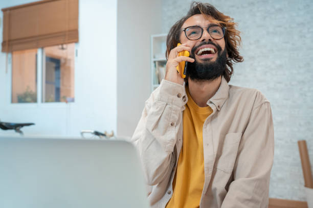 istock Man talking on the phone laughing in his modern workspace at home. 2175904550
