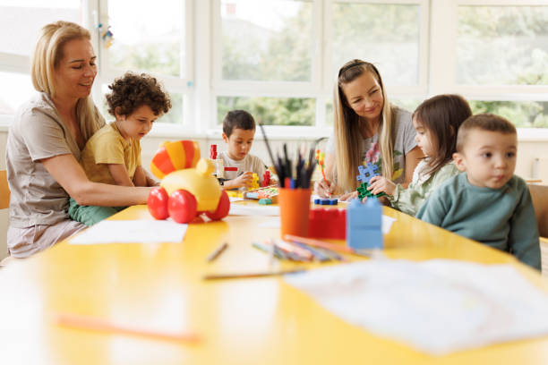 istock Group of children sit with their teachers at a table as they learn through play 2175909240