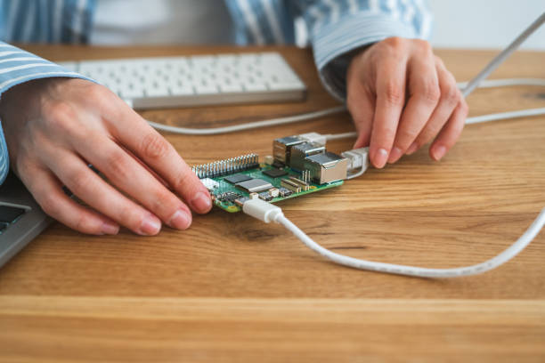 Close-up of hands connecting cables to small electronic circuit board