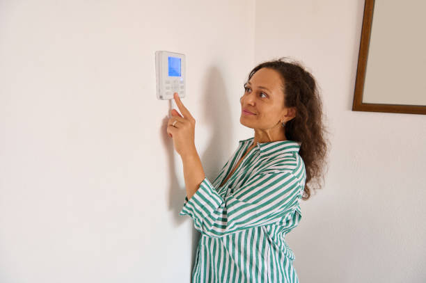 istock Woman adjusting thermostat for home temperature control 2175927559