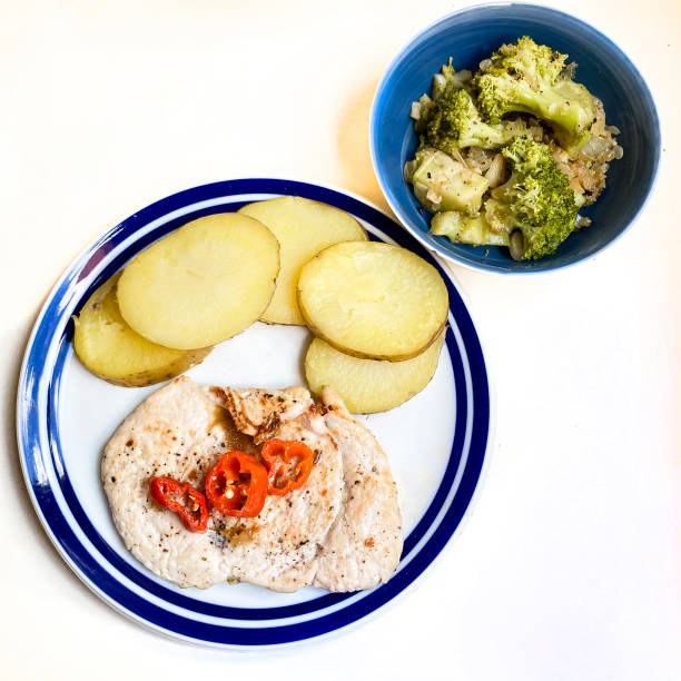 High angle view of slice of chicken ready to eat with potato and chilly pepper. Broccoli salad