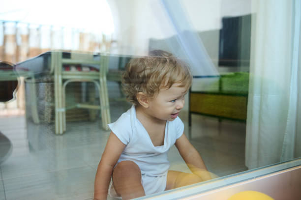 Cute little girl looks out the red window and making a face