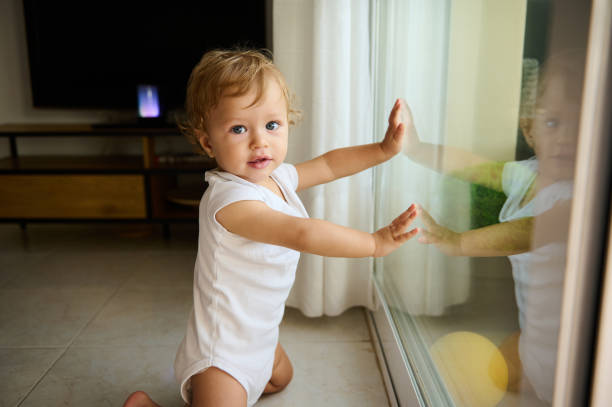Little boy at home looking trough the window waiting for his mother and father to come back home