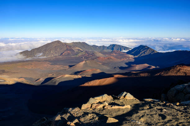 Volcanic landscape with some smaller craters of dormant volcanoes inside the huge Haleakala Crater (10020 ft tall) in Maui, Hawaii in the evening.