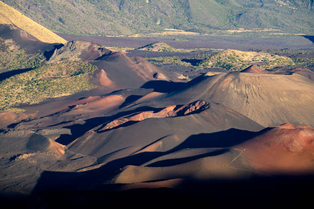 Volcanic landscape with some smaller craters of dormant volcanoes inside the huge Haleakala Crater (10020 ft tall) in Maui, Hawaii in the evening.