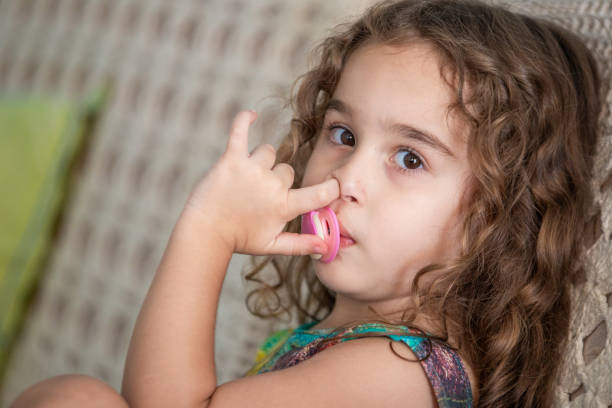 Goiania, Goias, Brazil – Setembro 20, 2024: A girl sucking a pacifier and picking her nose.