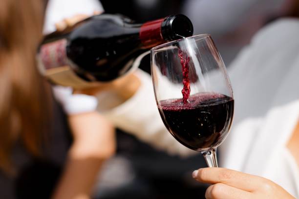 Close-up of a person pouring red wine into a glass at an outdoor event, showcasing wine's elegance A Close-up of a person pouring red wine into a glass at an outdoor event, showcasing the wine's elegance and clarity red wine stock pictures, royalty-free photos & images