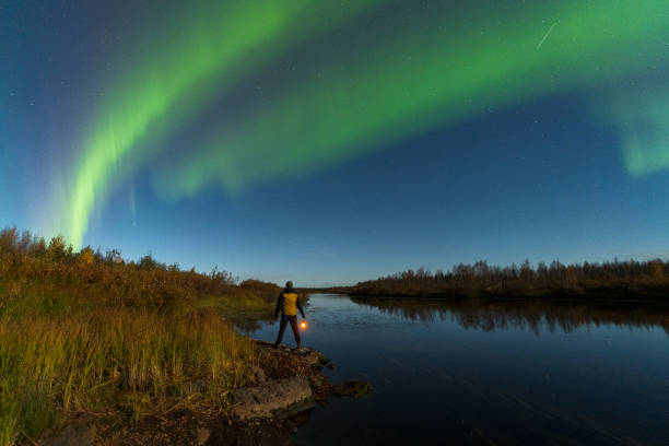 istock Man by the river under northern lights (aurora borealis), Finland 2175966321
