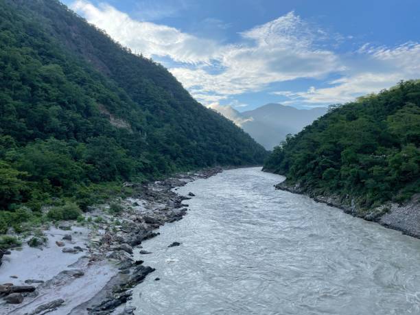 istock River flowing between lush green mountains under a blue sky. 2175969233
